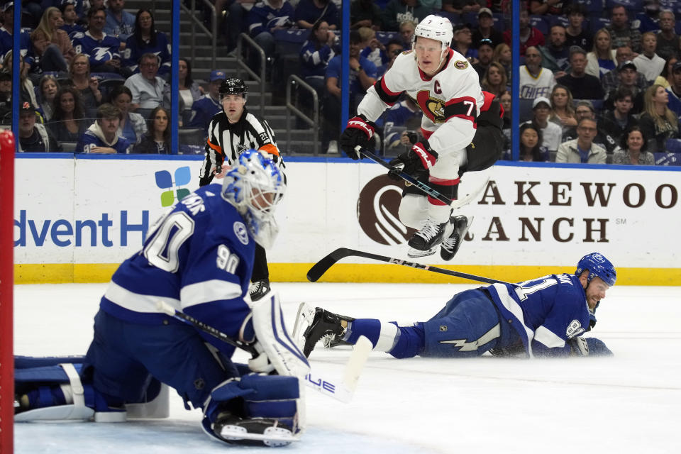 Ottawa Senators left wing Brady Tkachuk (7) leaps over Tampa Bay Lightning defenseman Erik Cernak (81) as he watches his shot get past Lightning goaltender Matt Tomkins (90) for a goal during the first period of an NHL hockey game Thursday, April 11, 2024, in Tampa, Fla. (AP Photo/Chris O'Meara)