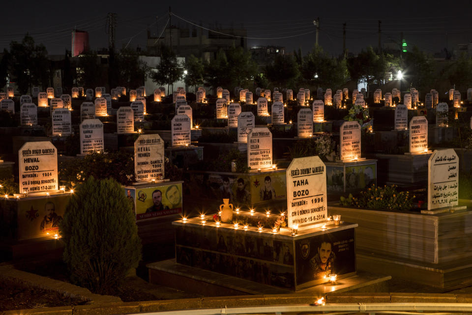 FILE - In this Oct. 31, 2019 file photo, candles adorn the graves of people killed during Syrian war, in the town of Qamishli, north Syria. The U.N. Commission of Inquiry on Syria said in a report released Monday, March, 1, 2021, that tens of thousands of civilians were arbitrarily detained in enforced disappearances during the country's 10-year conflict. The conflict has killed nearly half a million people, displaced half the country’s pre-war population of 23 million, including 5 million who are refugees abroad. (AP Photo/Baderkhan Ahmad, File)