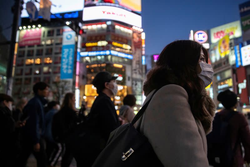 FILE PHOTO: A woman wearing a protective mask is seen at the scramble crossing in Shibuya shopping district in Tokyo as Japan deals with the coronavirus outbreak