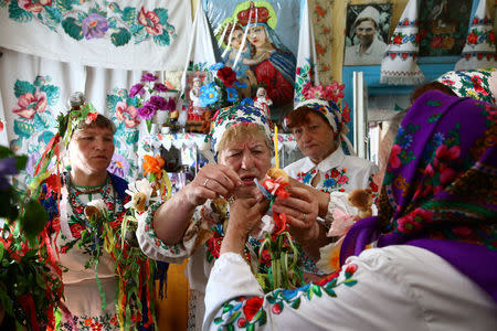 Women gather for a May-time ritual in honour of the pagan god Yurya when villagers don national dress and make offerings out of colourful ribbons and paper in the hope of plentiful harvests in the future, in the village of Pogost, Belarus, May 6, 2017. REUTERS/Vasily Fedosenko