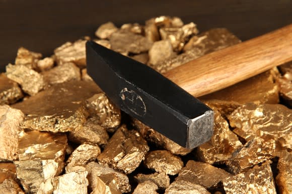 A hammer sitting atop a pile of gold pieces.
