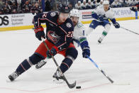 Columbus Blue Jackets' Jake Bean, left, tries to clear the puck as Vancouver Canucks' Conor Garland defends during the first period of an NHL hockey game Monday, Jan. 15, 2024, in Columbus, Ohio. (AP Photo/Jay LaPrete)