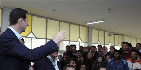 Syria's President Bashar al-Assad (L) speaks to displaced Syrians during his visit to them in the town of Adra in the Damascus countryside, March 12, 2014, in this handout photograph released by Syria's national news agency SANA. REUTERS/SANA/Handout via Reuters