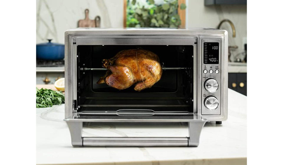 Stainless steel unit shown with rotisserie chicken cooking inside. 