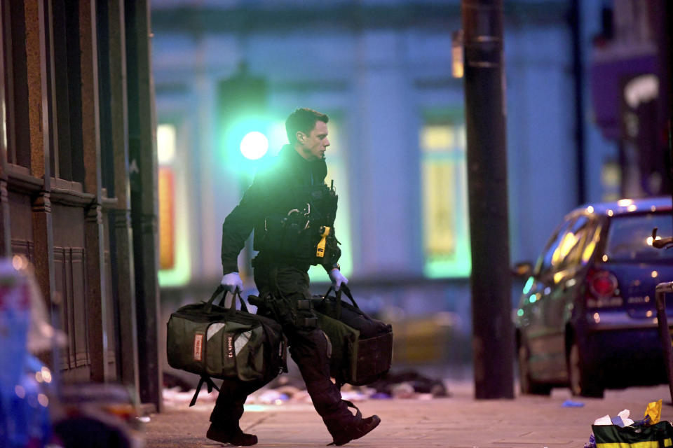 An armed police officer recovers medical bags near the scene of the stabbing. Source: AP