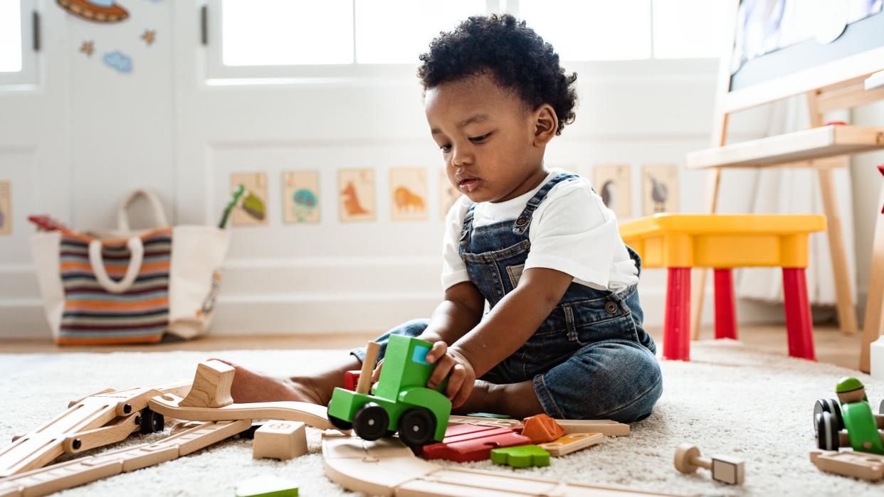 Cute little boy playing with a railroad train toy.