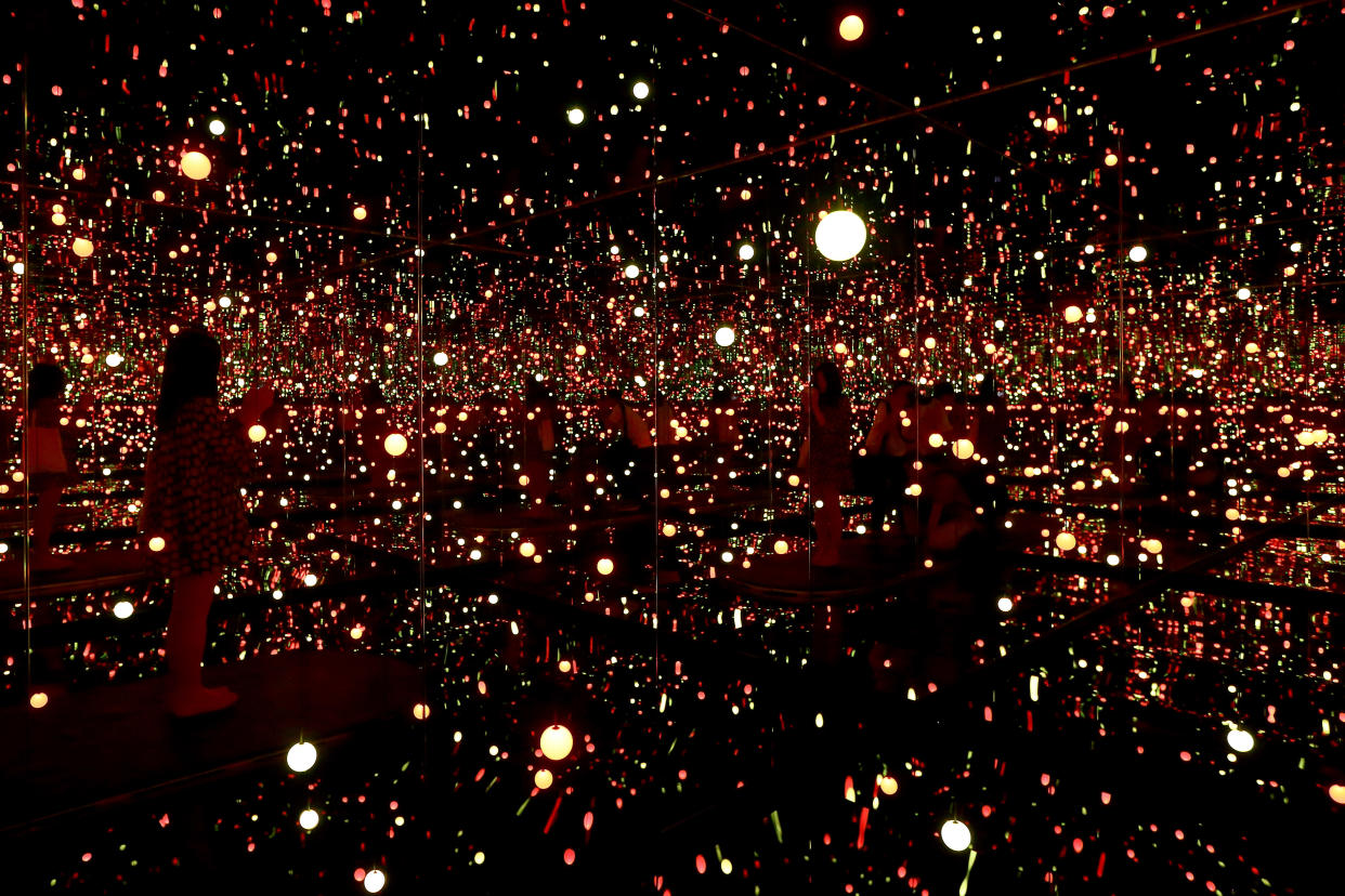 SINGAPORE - JUNE 06:  A visitor stands inside Japanese artist, Yayoi Kusama mirror, wooden panels, LED lights, metal, acrylic panels titled 'Infinity Room-Gleaming Lights of Souls' during a media preview at National Gallery Singapore on June 6, 2017 in Singapore. Yayoi Kusama: Life is the Heart of a Rainbow exhibition features over 120 works spanning 70 years of Kusama's artistic practise. The exhibition runs from June 9 to September 3, 2017.  (Photo by Suhaimi Abdullah/Getty Images)