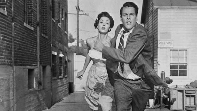 two people run away from an invading threat in a scene from 'invasion of the body snatchers,' a good housekeeping pick for best scary movies for kids