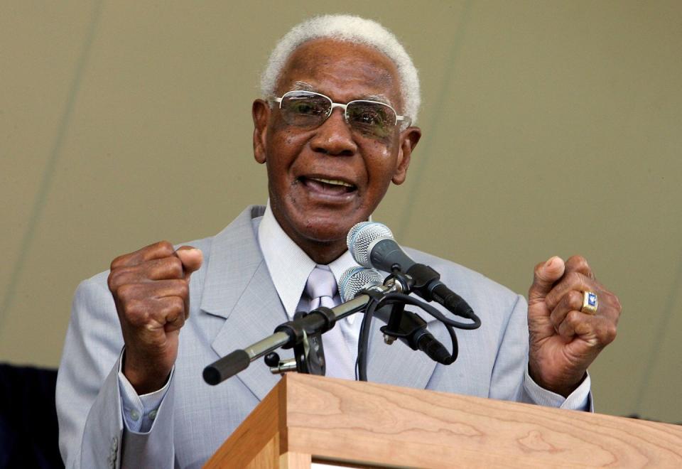 buck o'neil talking in front of a microphone at a podium