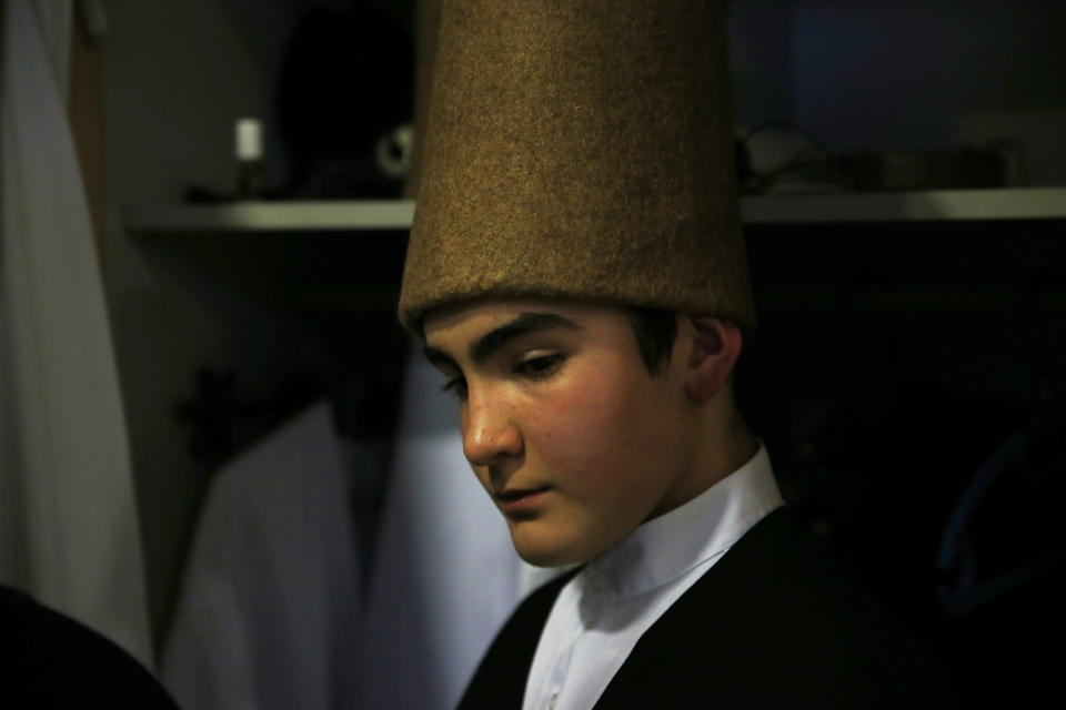 In this photo taken on Sunday, Dec. 16, 2018, a young whirling dervish of the Mevlevi order concentrates in the locker room prior to a Sheb-i Arus ceremony in Konya, central Turkey. Every December the Anatolian city hosts a series of events to commemorate the death of 13th century Islamic scholar, poet and Sufi mystic Jalaladdin Rumi. (AP Photo/Lefteris Pitarakis)