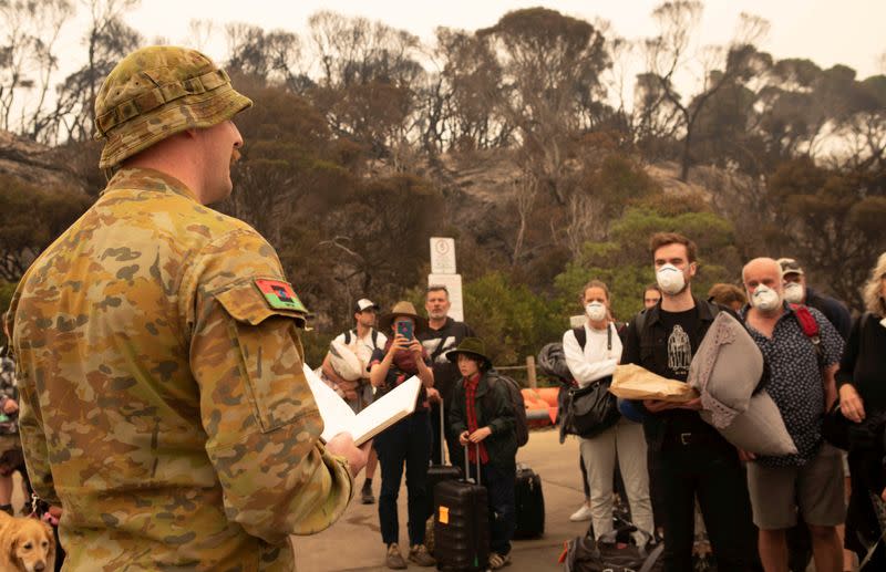 An image obtained on January 3, 2020, shows Amphibious Beach Team Commander, Lieutenant Declan Michell briefing bushfire evacuees prior to them boarding HMAS Choules at Mallacoota