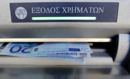 FILE PHOTO: Sixty euros, the maximum amount allowed after the imposed capital controls in Greek banks, are seen during a withdrawal operation at a bank branch ATM in central Athens
