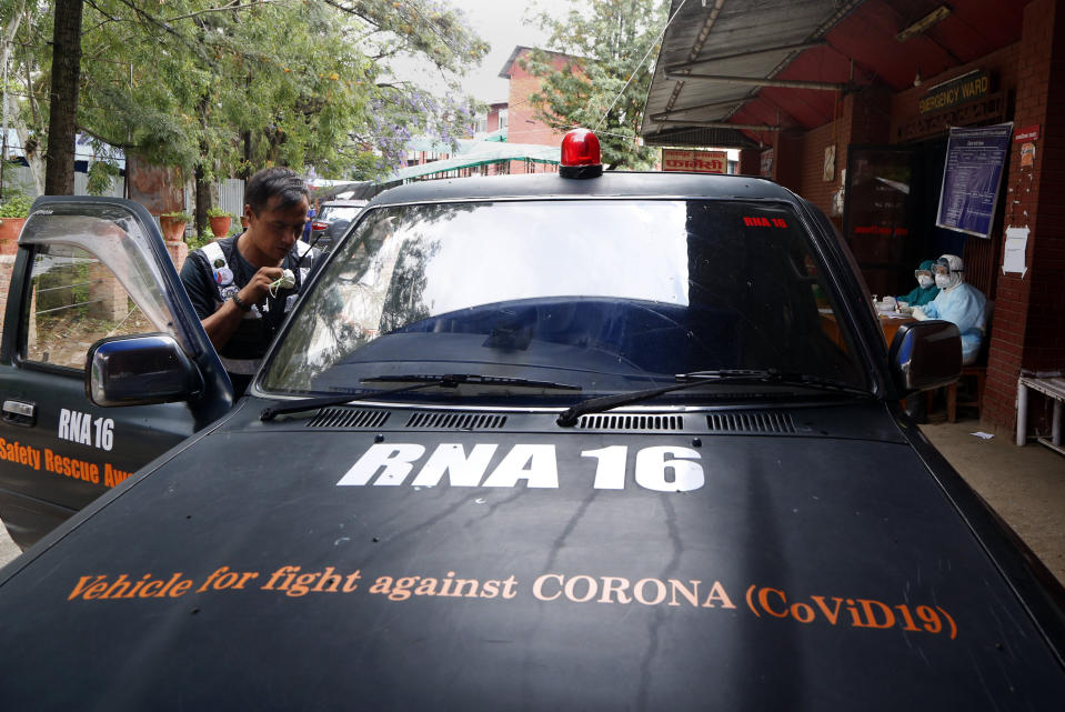 Arun Saiju of the RNA-16 volunteer group, coordinates with other volunteers on a walkie-talkie during lockdown at hospital in Bhaktapur, Nepal, Tuesday, May 26, 2020. RNA-16 stands for “Rescue and Awareness” and the 16 kinds of disasters they have prepared to deal with, from Nepal’s devastating 2015 earthquake to road accidents. But the unique services of this group of three men and a woman in signature blue vests in the epidemic amount to a much greater sacrifice, said doctors, hospital officials and civic leaders. (AP Photo/Niranjan Shrestha)
