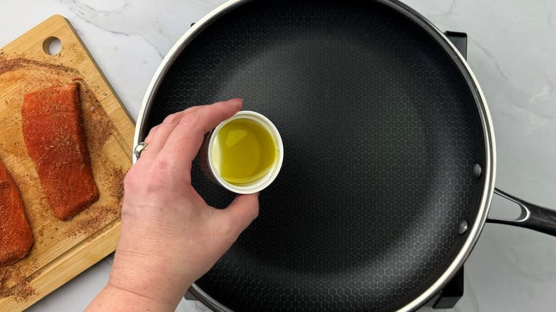 hand pouring oil into pan