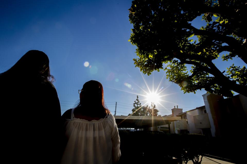 A woman and her teen daughter stand together