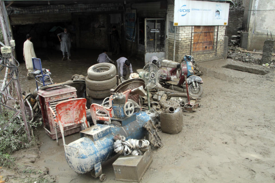 Pakistani men look for belongings from their flood-hit shops in Mingora, the capital of Swat valley in Pakistan, Saturday, Aug. 27, 2022. Officials say flash floods triggered by heavy monsoon rains across much of Pakistan have killed nearly 1,000 people and displaced thousands more since mid-June. (AP Photo/Naveed Ali)