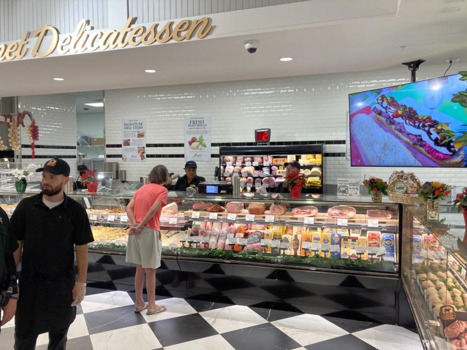 One of the first customers on Tuesday morning, a woman speaks with employees behind the deli counter at Joseph's Classic Market in West Palm Beach.