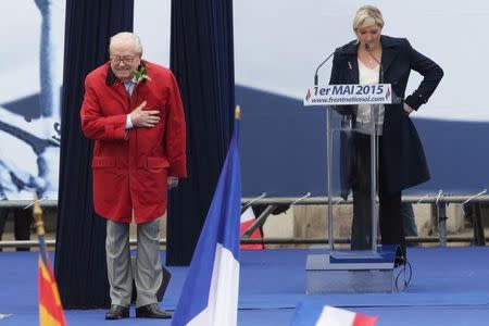 France's far-right National Front political party leader Marine Le Pen (R) watches as her father Jean-Marie Le Pen, party founder and honorary president, reacts on the podium at their traditional May Day tribute to Joan of Arc in Paris, France, May 1, 2015. REUTERS/Philippe Wojazer