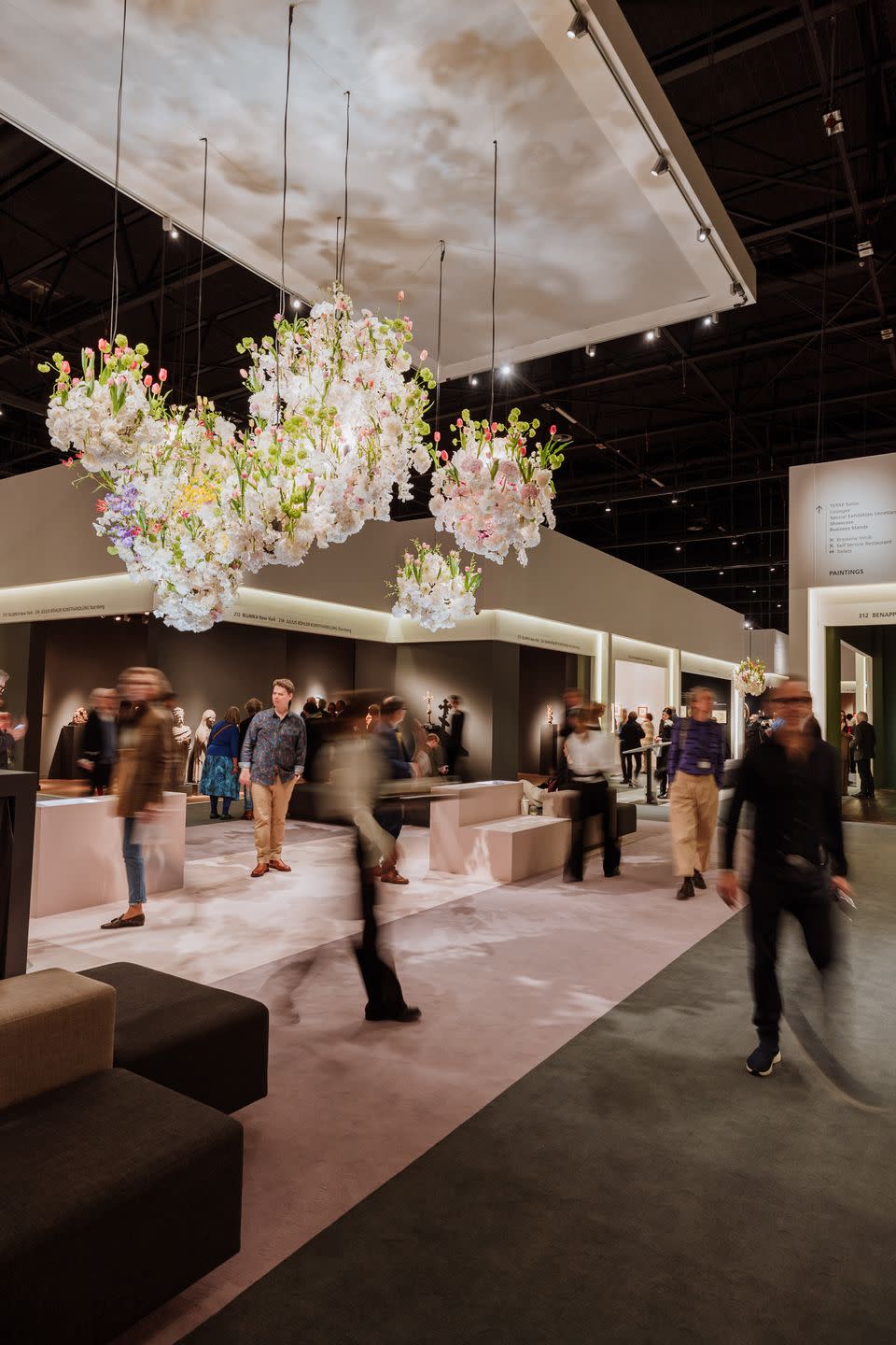 a group of people walking in a building with flowers on the ceiling