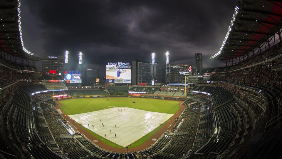 A tarp covers the infield during a rain delay in the third inning of a baseball game between the Atlanta Braves and the New York Mets, Wednesday, Aug. 17, 2022, in Atlanta. (AP Photo/Hakim Wright Sr.)