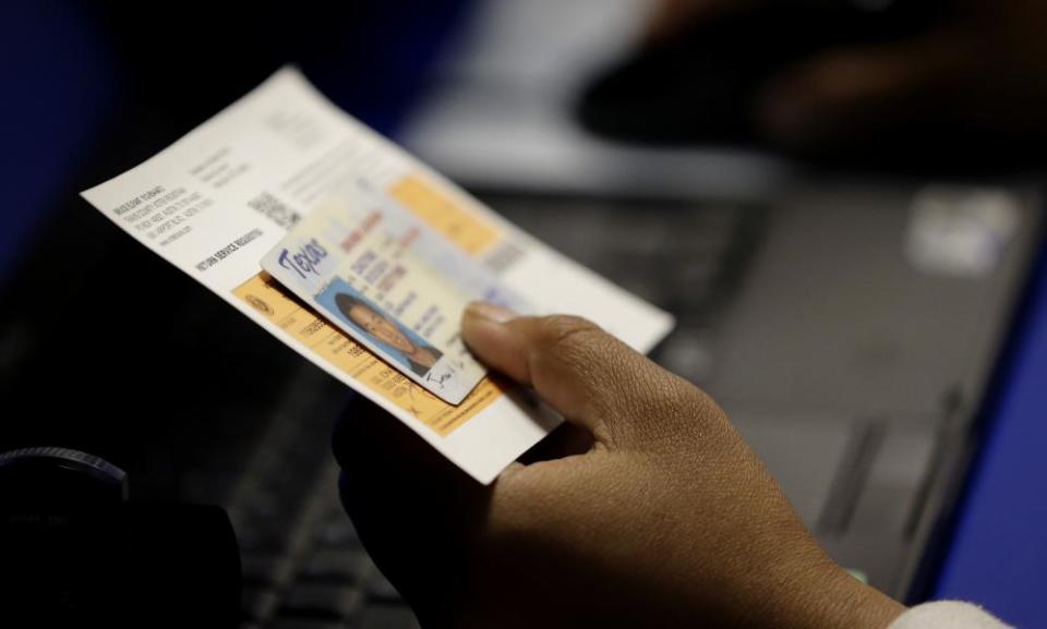 An election official checks a voter’s photo identification in Austin, Texas on 26 February 2014.