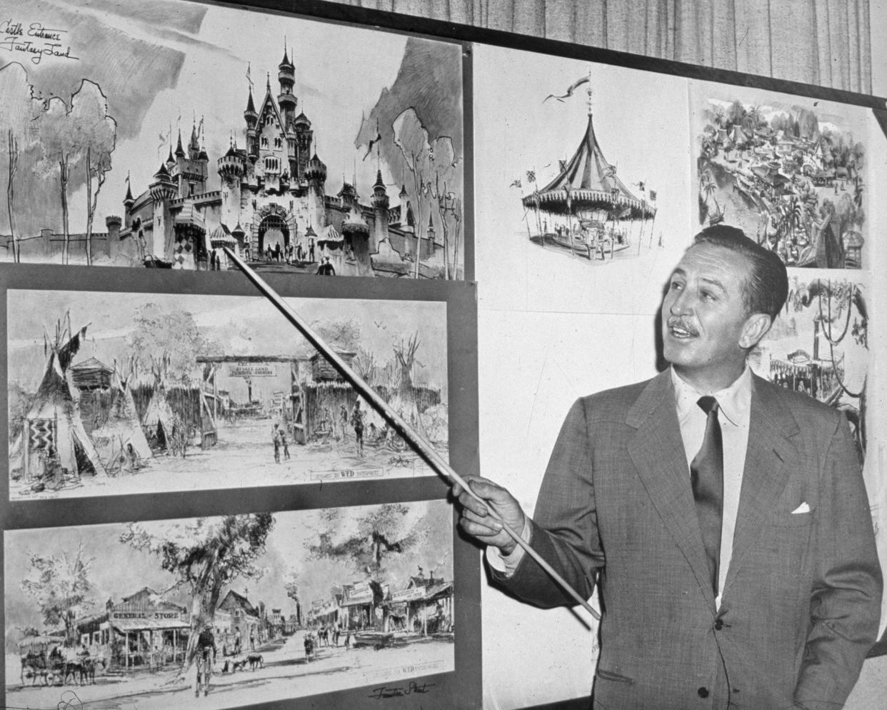 American producer, director, and animator Walt Disney (1901 - 1966) uses a baton to point to sketches of Disneyland, 1955.
