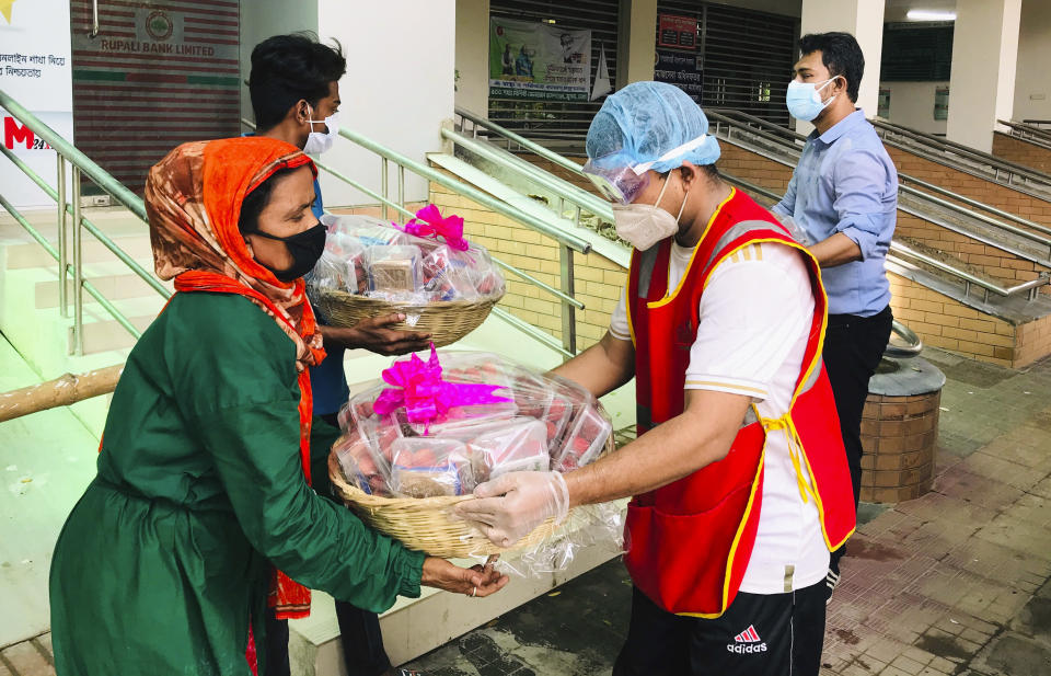 Members of Bidyanondo Foundation distribute packages to people receiving them on behalf of COVID-19 patients in Dhaka, Bangladesh, Saturday, June 6, 2020. The Bangladeshi group of volunteers is providing COVID-19 patients with fruit baskets and “get well soon” cards to keep their spirits up amid reports that many patients are being ostracized by their families and neighbors. The group stepped in after disturbing news reports that a woman has been abandoned in a forest by her family after she developed coronavirus symptoms. (AP Photo/Al-emrun Garjon)