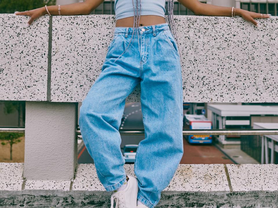 woman wearing loose jeans and a crop top with a bucket hat