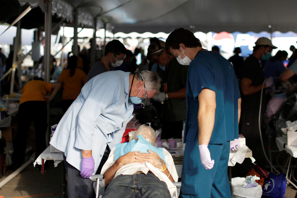 A dentist speaks with a man in treatment