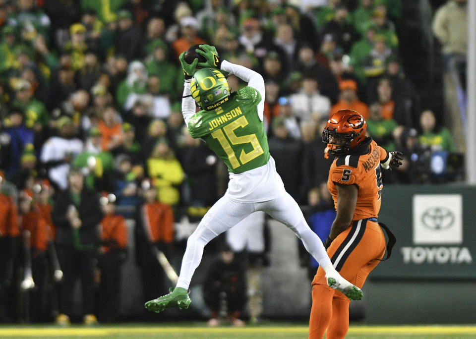 Oregon wide receiver Tez Johnson (15) catches a pass in front of Oregon State linebacker Easton Mascarenas-Arnold (5) during the first half of an NCAA college football game Friday, Nov. 24, 2023, in Eugene, Ore. (AP Photo/Mark Ylen)