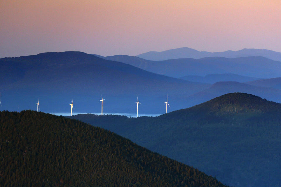 A line of wind turbines catch the breeze at sunrise in the western Maine mountains on July 26, 2017, in Weld, Maine. (Robert F. Bukaty / AP)