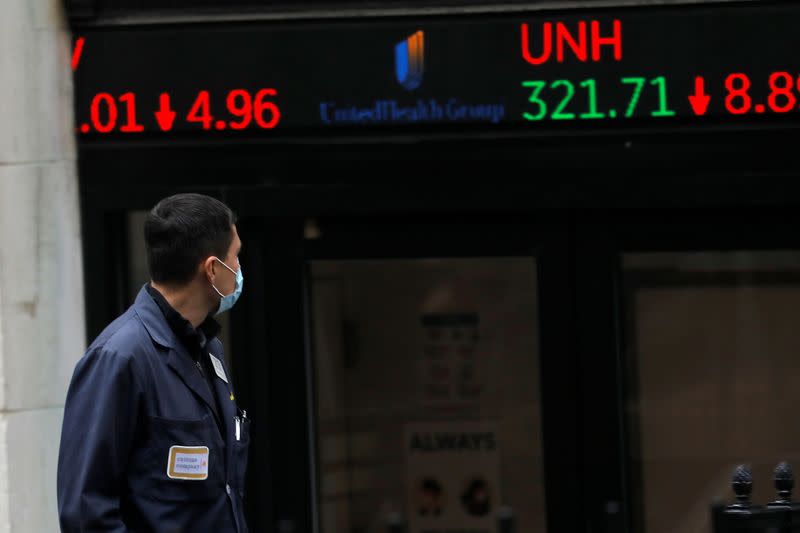 A trader walks past a digital stock price display outside the New York Stock Exchange in New York