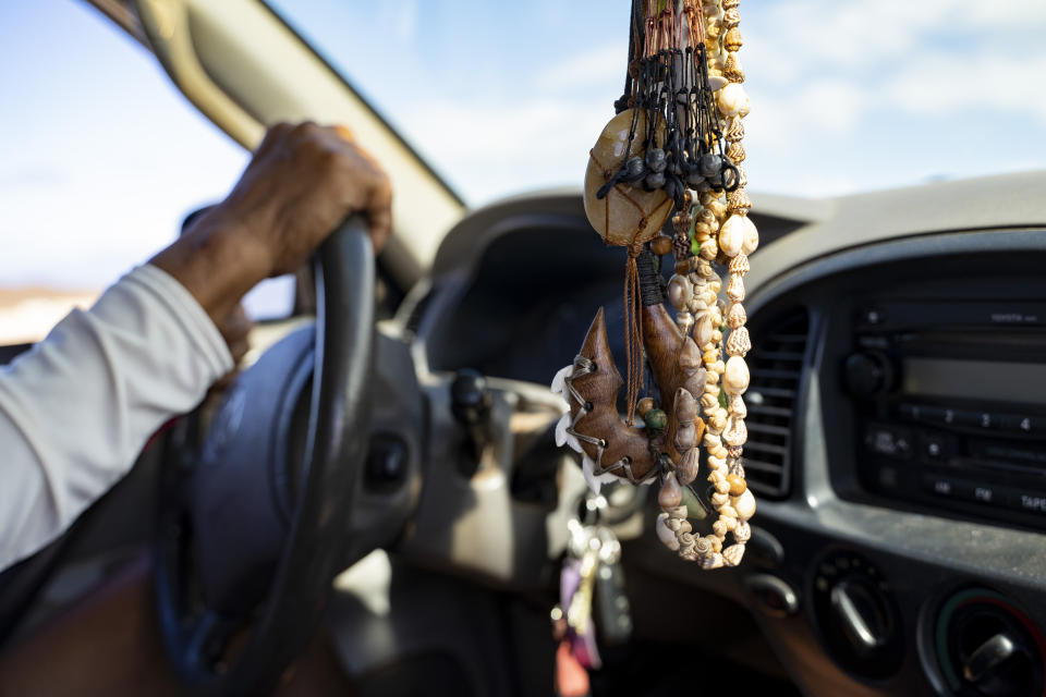 Necklaces made with shells and a fish hook, also known as a makau, are hung in Abraham "Snake" Ah Hee's truck on Friday, Feb. 23, 2024, in Lahaina, Hawaii. (AP Photo/Mengshin Lin)