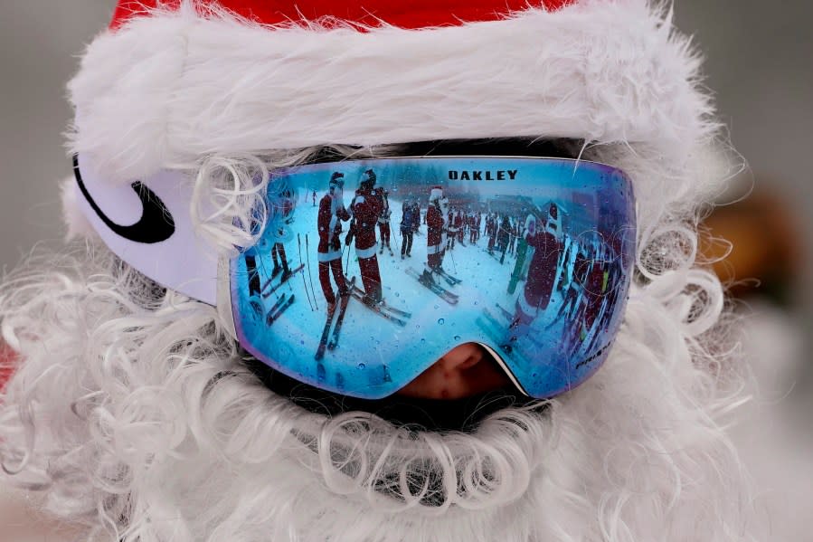 Skiers dressed as Santa Claus are reflected in another skier’s goggles, Sunday, Dec. 10, 2023, at the Sunday River ski resort in Newry, Maine. The annual Santa Sunday event raises money for local charities. (AP Photo/Robert F. Bukaty)