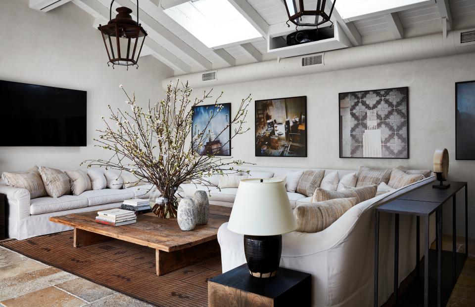 In the poolhouse, a sofa wraps around a custom reclaimed-wood cocktail table. Indian textiles cover the pillows.