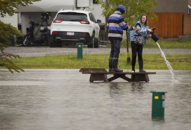 A teenager pours water out of her boot after wading through flood waters in a park in Claresholm, Alta.