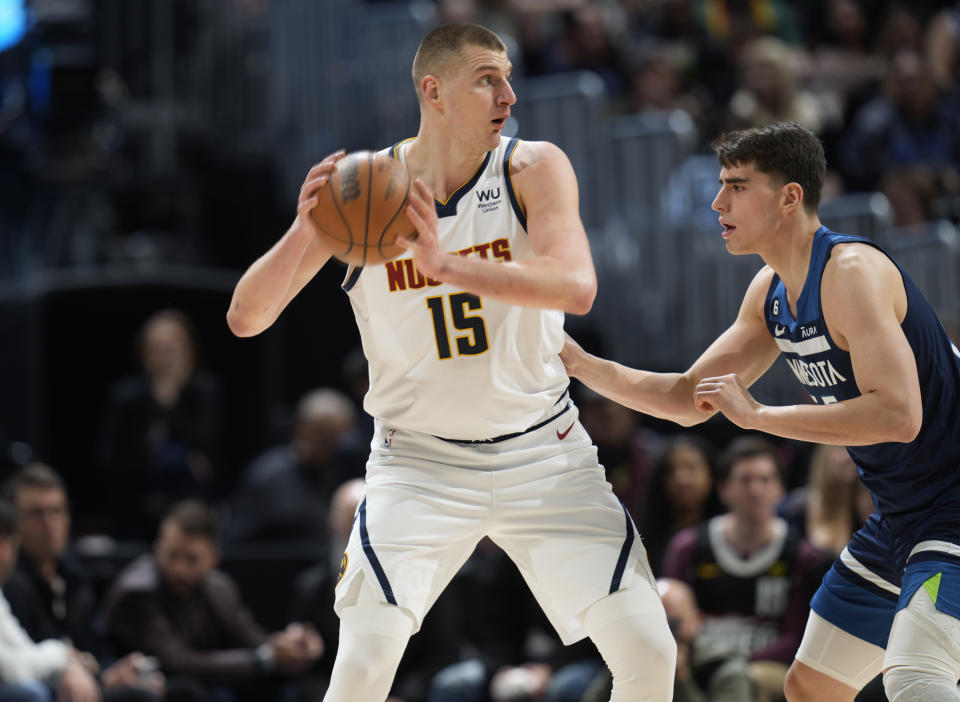 Denver Nuggets center Nikola Jokic, left, looks to pass the ball as Minnesota Timberwolves center Luka Garza defends in the first half of an NBA basketball game Tuesday, Feb. 7, 2023, in Denver. (AP Photo/David Zalubowski)