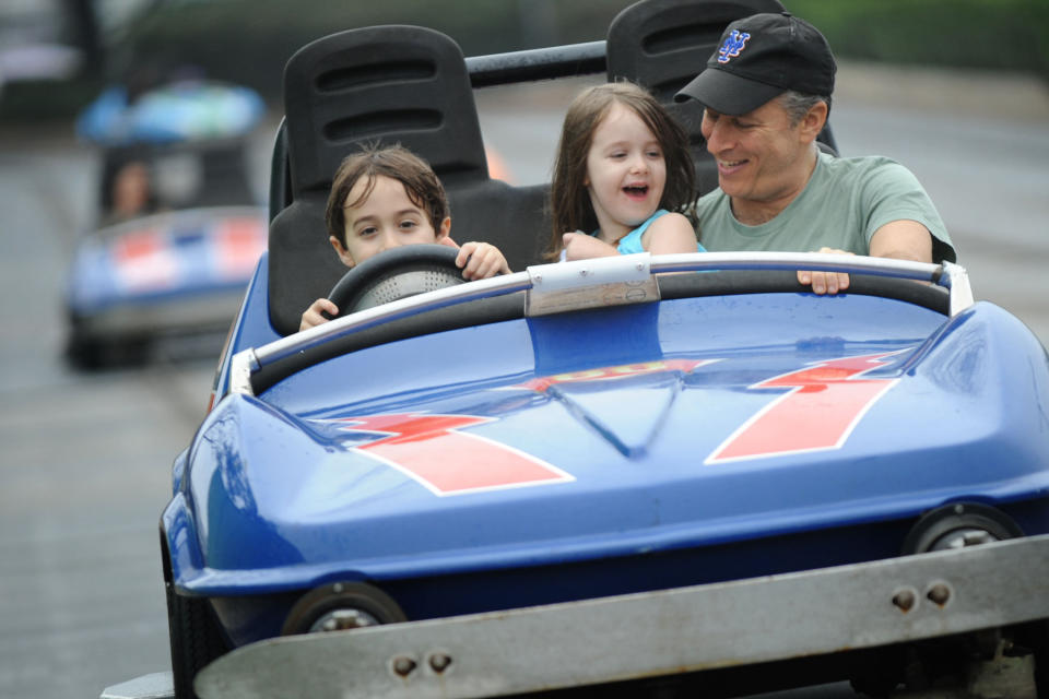 LAKE BUENA VISTA, FL - FEBRUARY 04:  In this handout photo provided by Disney, Emmy Award-winning TV host and Grammy Award-winning comedian Jon Stewart takes a ride on the Tomorrowland Indy Speedway with his children Nate (left, age 6) and Maggie (center, age 5) at the Magic Kingdom theme park on February 4, 2011 in Lake Buena Vista, Florida.  The February 4 visit took place on Maggie's 5th birthday, and Stewart and his family celebrated the occasion with friends at the Walt Disney World theme park.  (Photo by David Roark/Disney via Getty Images)