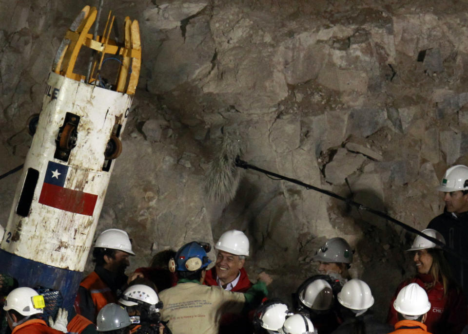 FILE - Chilean President Sebastian Pinera hugs rescued miner Raul Bustos after Bustos was lifted from the collapsed San Jose gold and copper mine where he had been trapped with 32 other miners for over two months, near Copiapo, Chile, Oct. 13, 2010. Piñera died on Tuesday, Feb. 6, 2024 in a helicopter crash in Lago Ranco, Chile, according to Chilean Interior Minister Carolina Tohá. (AP Photo/Jorge Saenz, File)