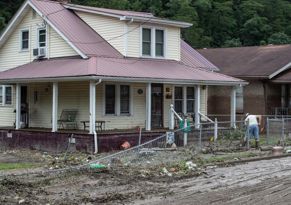 A man in the Upper Bottoms area of Letcher County, Kentucky shovels the mud from in front of his home after flood waters inundated low living areas of the eastern part of the state. July 29, 2022