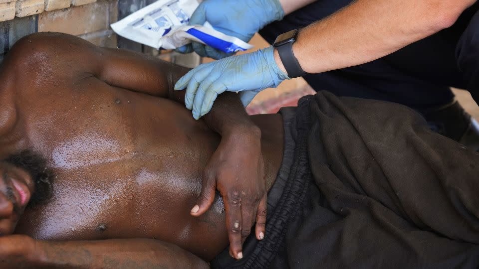 Austin-Travis County Emergency Medical Services medic Capt. Darren Noak applies a chemical ice pack to a man in Austin, Texas, on July 12. - Jay Janner/Austin American-Statesman/AP