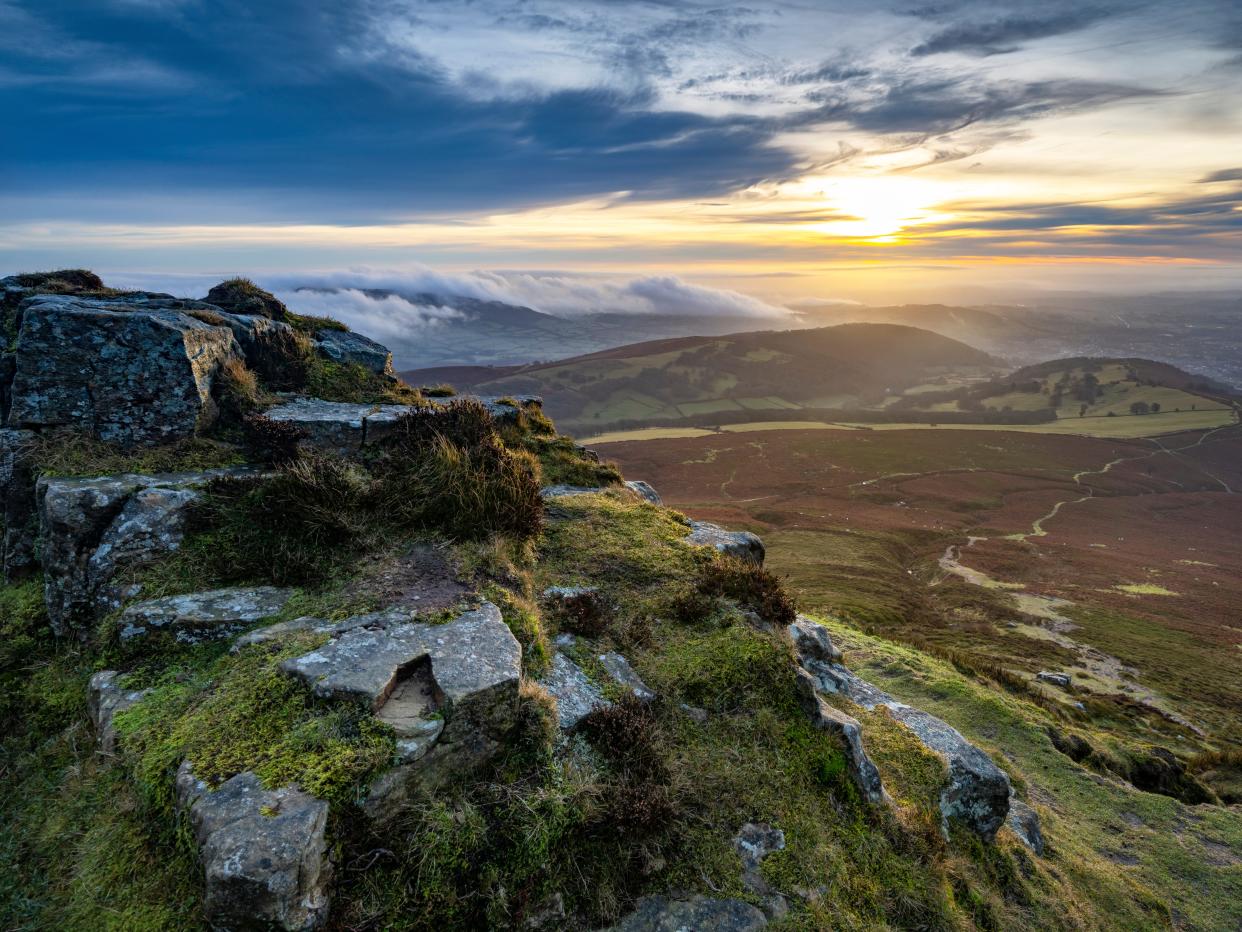 Rolling green hills in Wales with protruding rock formations