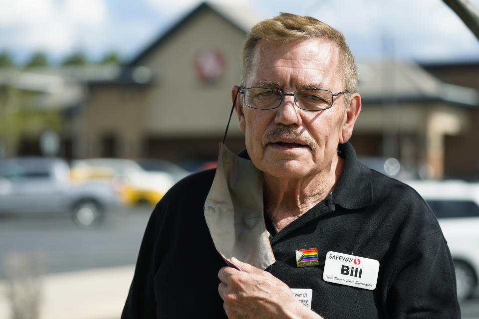 In this Wednesday, May 19, 2021, photograph, Bill Easton, a checker at a Safeway grocery store, is shown in the shopping center in which the store is located in Aurora, Colo. Easton, like many other workers in retail sales jobs, is fully vaccinated but is concerned about risks posed as retailers change their mask-wearing policies for customers. (AP Photo/David Zalubowski)