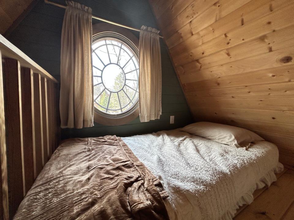 bed on floor under circle window with curtains in rapunzel's cottage