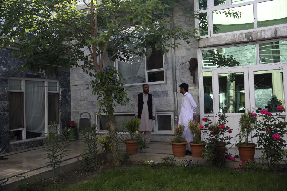 In this Wednesday, May 20, 2020 photo, Behtarin Paktiawal, left, Behtarin Paktiawal, a brother of Dr. Yousuf Aryubi who along with two siblings died from COVID-19, stands in the courtyard of his house after recovering from the coronavirus, in Kabul, Afghanistan. Dr. Aryubi's family assumed they just had a bad cold, as one after another, they came down with fevers and coughs -- all because one of the Afghan capital's main hospitals never told them the results of his coronavirus test. Their tragedy points to how a broken-down health system, slow government response and public attitudes have left Afghanistan deeply vulnerable to the global pandemic. (AP Photo/Rahmat Gul)