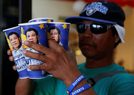 A mall parking attendant and supporter of presidential candidate Rodrigo Duterte for the May 9 election, holds "Big Gulp" soda cups he bought from convenience store 7-Eleven, in Paranaque, Metro Manila, Philippines April 25, 2016. REUTERS/Erik De Castro