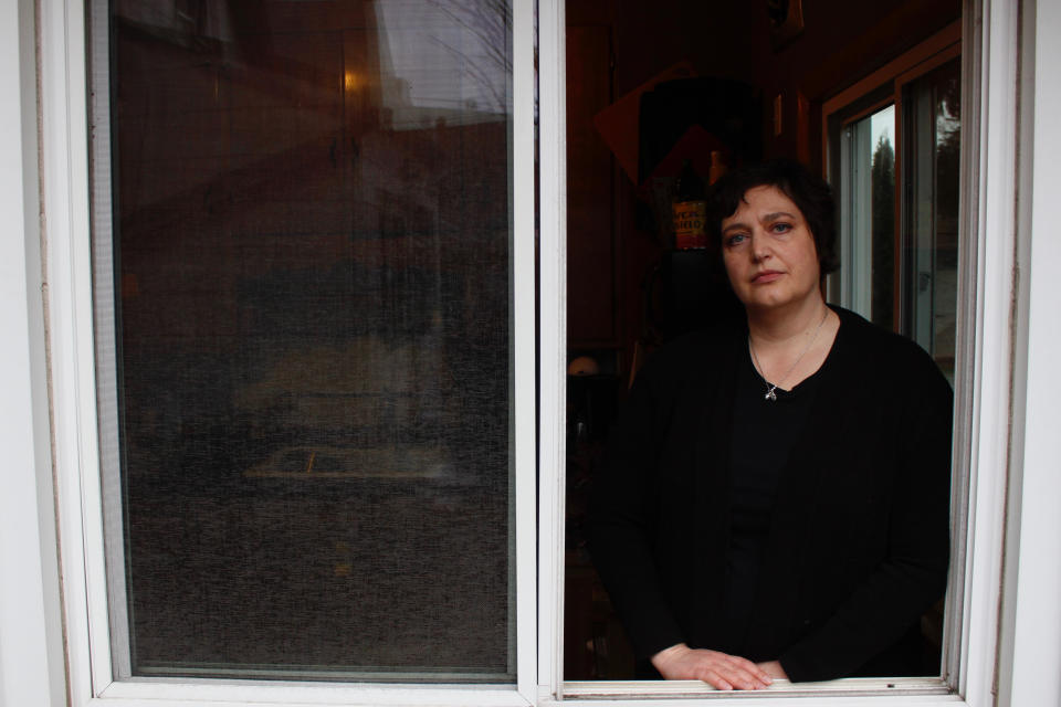 In this April 29, 2020 photo, Julie Hitchcock stands in window at her Milwaukee home. Hitchcock, 49, said she worries about getting sick or unknowingly infecting someone else, anxiety that's heightened because she was on a ventilator for two weeks last fall after developing pneumonia. As the coronavirus pandemic upends lives across the nation, a new poll conducted by NORC at the University of Chicago for the Data Foundation found that most Americans reported feeling nervous, depressed, lonely or hopeless in the last week. (AP Photo/Carrie Antlfinger)