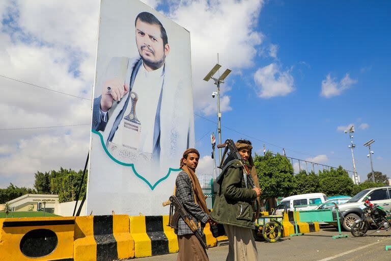 Combatientes yemeníes pasan junto a un gran retrato del líder hutí Abdulmalik al-Huthi en una calle de Saná el 18 de enero de 2024. (MOHAMMED HUWAIS / AFP)