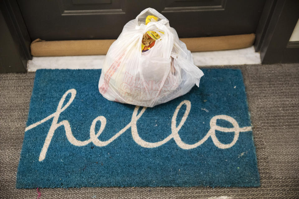 Groceries delivered by the nonprofit organization "We Are Family DC," sit on a welcome mat that says "hello," Saturday, March 21, 2020, in Washington. Seniors are being encouraged to stay in their homes due to the risk of the COVID-19 coronavirus. (AP Photo/Jacquelyn Martin)