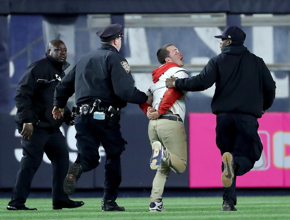 A fan is taken off the field by security after he ran onto the field in seventh inning during the game between the New York Yankees and the Minnesota Twins at Yankee Stadium on April 24, 2018 in the Bronx borough of New York City. (Photo by Elsa/Getty Images)